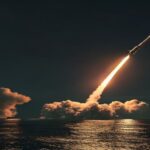 A photorealistic image of a North Korean missile launch at night, with a trail of fire and smoke against a dark sky, seen from a distance over the sea. The missile is mid-air, leaving a bright exhaust