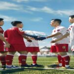 A photorealistic image of a North Korean football team in red uniforms shaking hands with South Korean players in white uniforms on a football field, with flags of both countries in the background, un