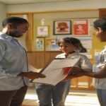 A photorealistic image of a social worker handing a folder to a grateful family at a municipal office in Spain. The room is bright and welcoming, with posters about social services on the wall. The fa