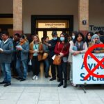 A photorealistic image of a Spanish town hall registration office with a long queue of diverse people looking worried, papers in hand, with a sign 'Empadronamiento' and another sign 'Ayudas Sociales'