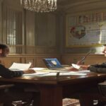 A photorealistic image of a meeting room in a government building, with two people sitting at a table with documents and a laptop, one holding a pen, the other gesturing. The room has a Spanish flag a